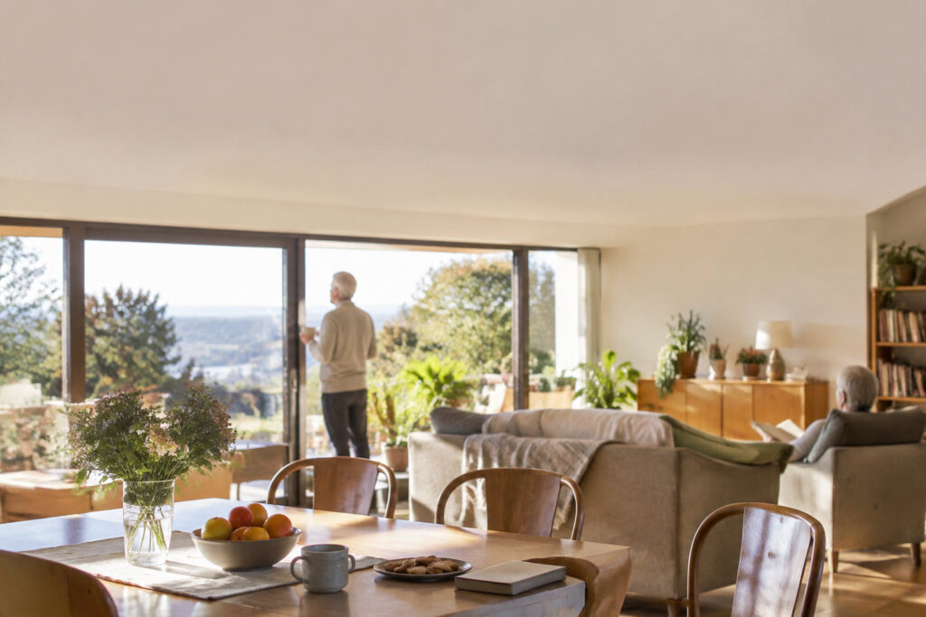 Intérieur chaleureux et lumineux d'une maison partagée pour seniors avec des personnes profitant de la vue et de la lecture.