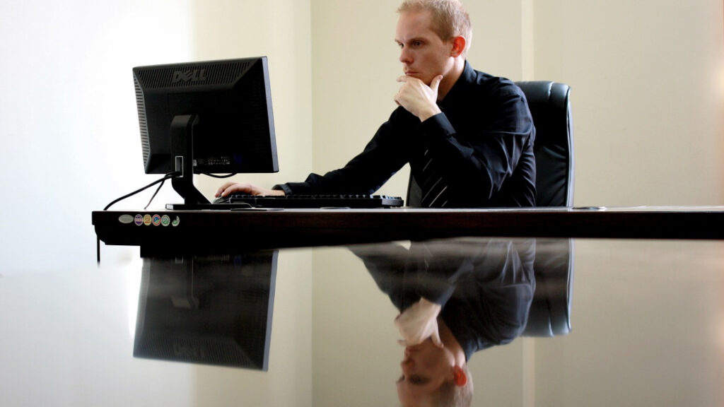 Un homme consulte son ordinateur au bureau.